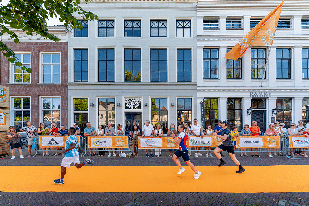 Lopers op de oranje finishloper in de Oost-Voorstraat, met publiek langs de dranghekken