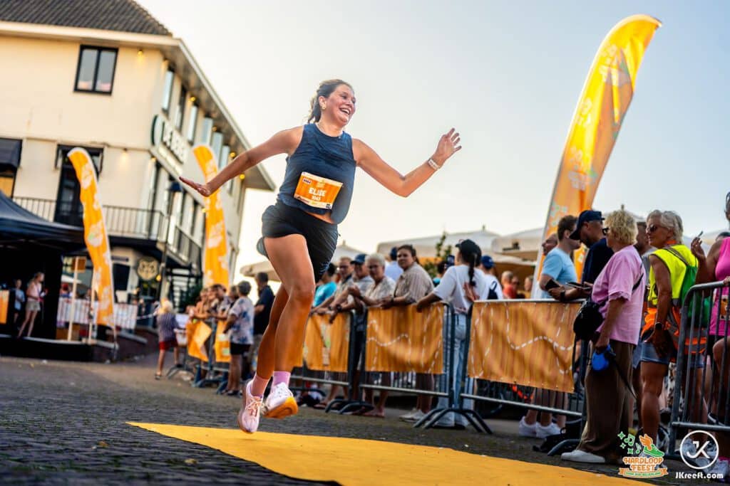 Loopster springt juichend over de oranje finishloper