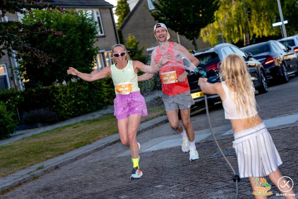 Kinderen langs de route spuiten lopers nat met de tuinslang