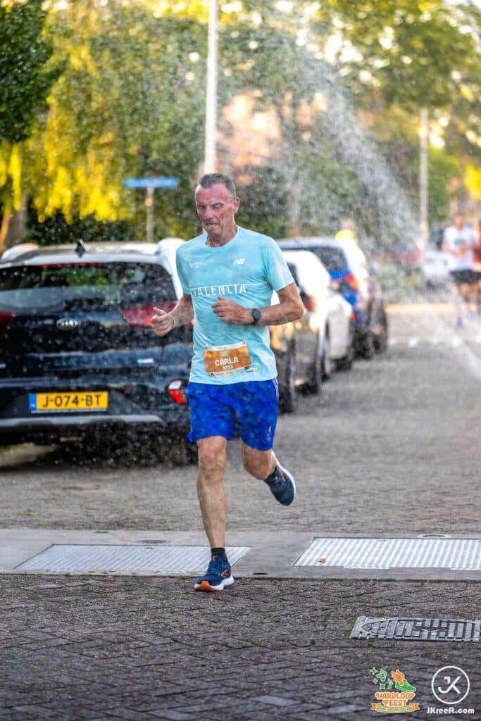Loper rent door een verkoelende waterstraal langs de route
