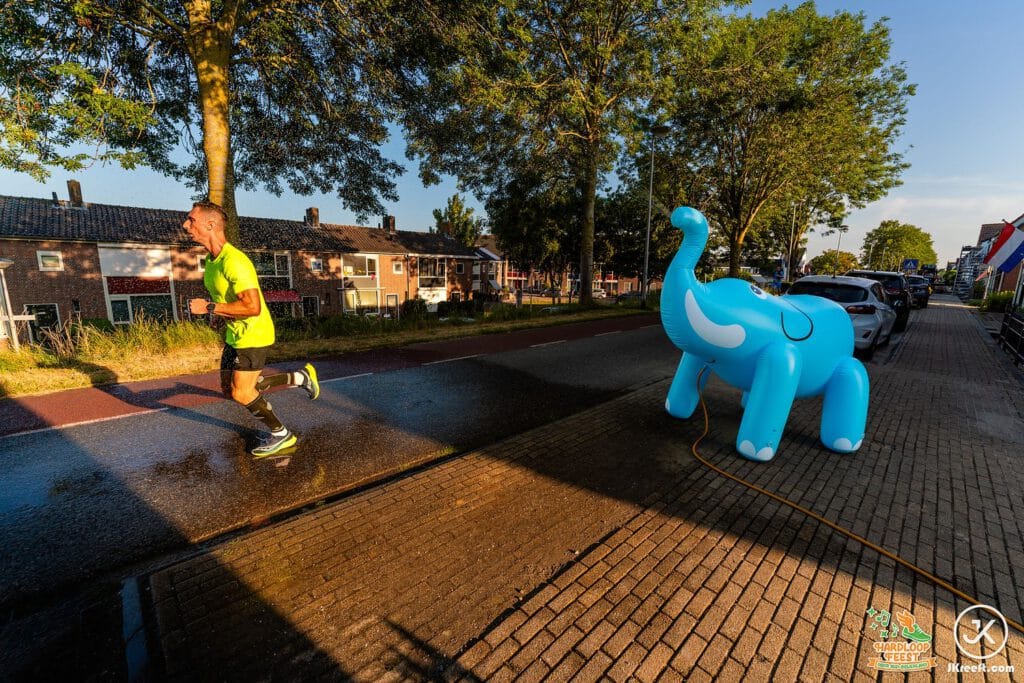 Loper passeert een opblaasbare blauwe olifant langs het parcours