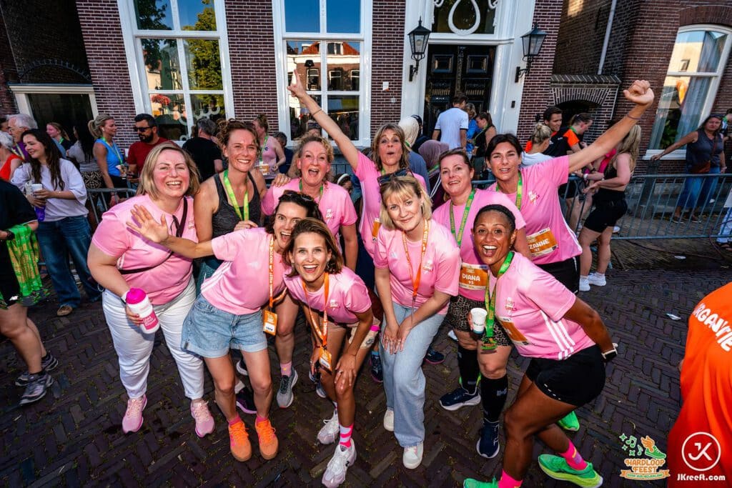 Groep loopsters in roze shirts juicht na de finish