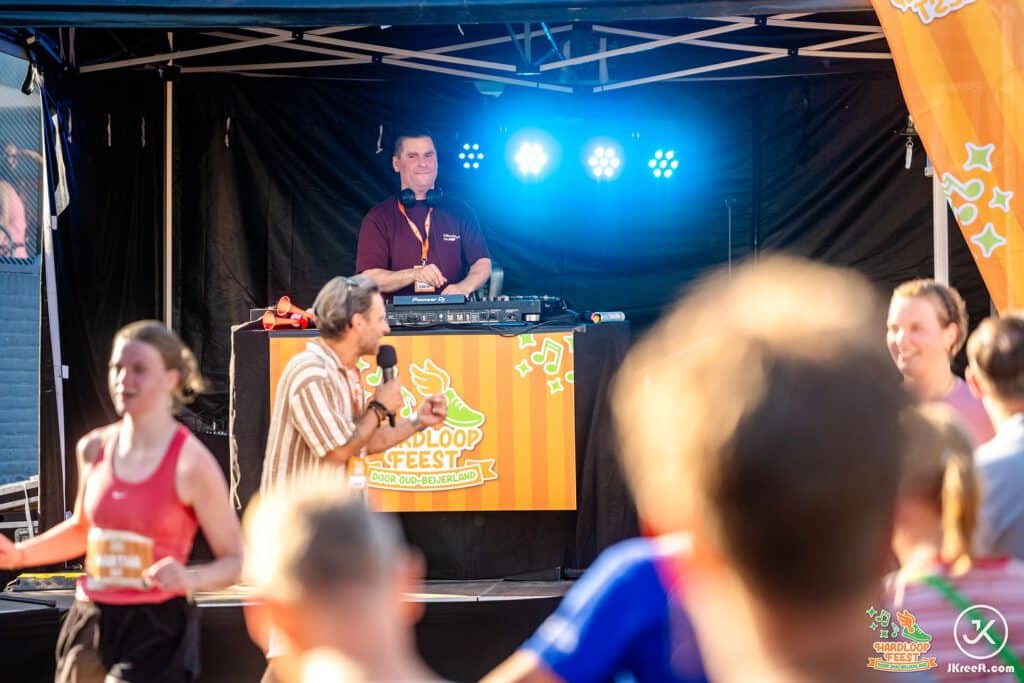 DJ en presentator op het podium langs de route