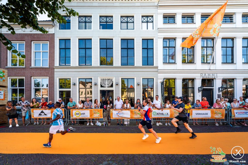 Lopers op de oranje finishloper voor de witte panden in het centrum