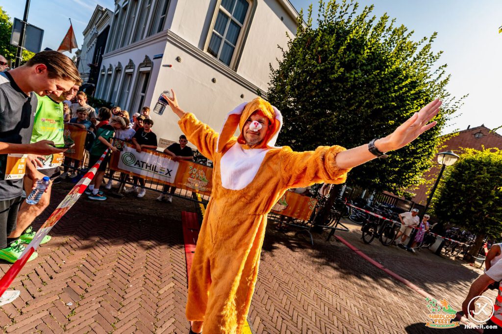 Loper in een oranje dierenpak spreidt zijn armen op het parcours