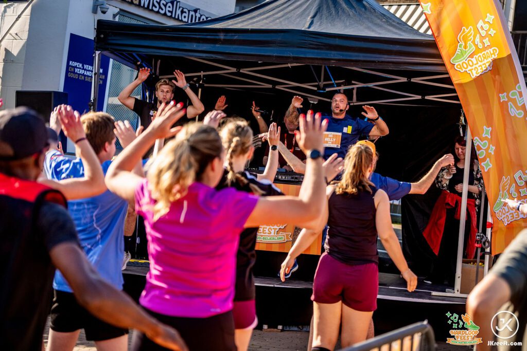 Lopers doen met de armen in de lucht de warming-up mee bij het podium